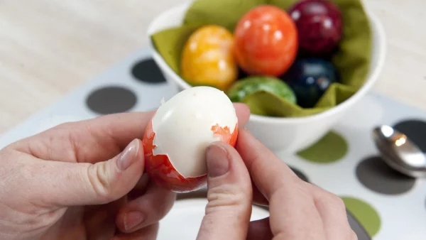 Eier haltbar gekochte gefärbte Eier in sanften Farben in einer Schale ein Ei schälen