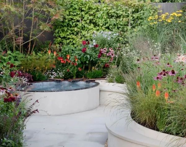 moderne Gartengestaltung Ideen Kurven im Garten weiße Beeteinfassung üppige Gartenpflanzen und Blumen 