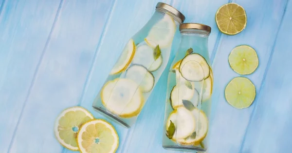 Zitronenwasser trinken vor dem Schlafengehen zwei Flaschen mit Zitronenscheiben und Wasser