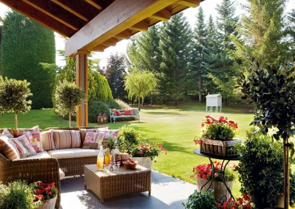 Überdachte Terrasse mit bequemen Outdoor Möbeln eingerichtet und viele Pflanzen ringsherum