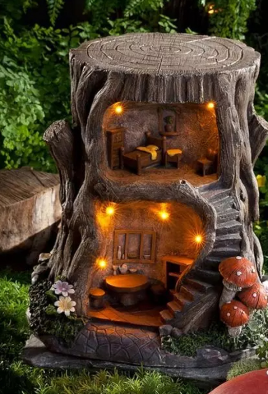 Baumstamm als Gartendeko ein Puppenhaus im Inneren des Baumstumpfs beleuchtet