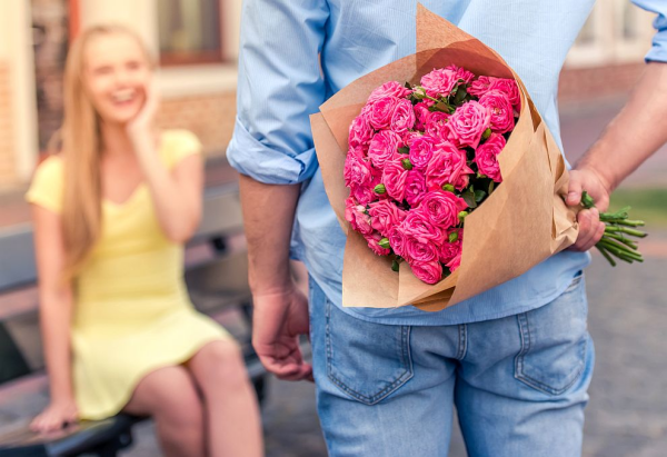 Blumen mit negativer Symbolik junger Mann mit großem Blumenstrauß überrascht seine Liebste rosa Rosen