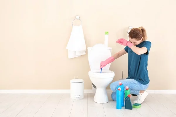 natürliche Reinigungsmittel gegen Urinstein junge Frau Handschuhe Toilette saubermachen mit chemischen Mitteln