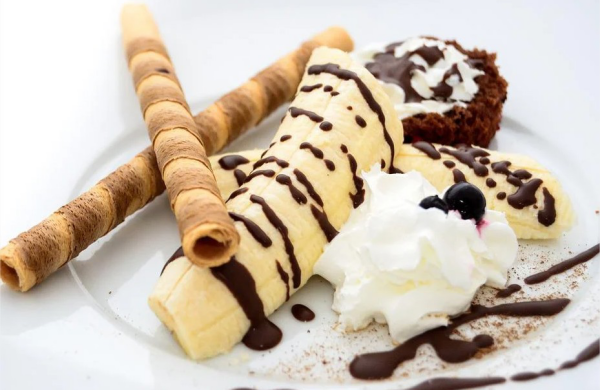 Bananen Desserts köstlich mit warmer Schokolade gegossen Zimtstangen Schlagsahne Muffin