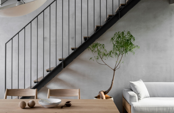 Japanisches Design graue Betonwand Zimmerdecke Esstisch Stühle aus hellem Holz weißes Sofa Treppe Minimalismus