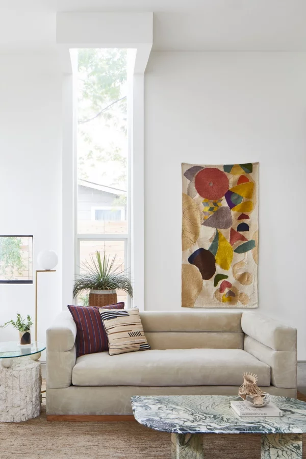 Dominierende Sommerfarben schickes Wohnzimmer helles Grau an der Wand kunstvolles Wandbild hellbeiges Sofa bunte Kissen