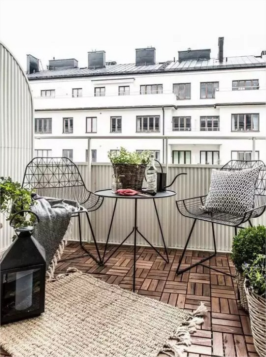 Gartenmöbel aus Metall Terrasse in der Stadt Kaffeeecke Holzbodenbelag grüne Kübelpflanzen
