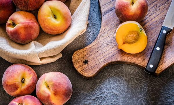 Pfirsiche lagern rustikaler Look in einer Schüssel mit Tuch bedeckt reife Früchte auf dem Brett schneiden