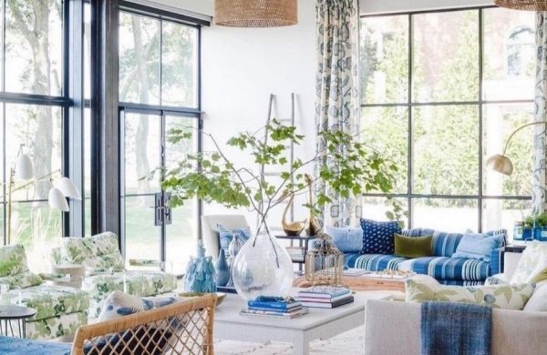 Verglaste Veranda in blau weiß gestaltet mit grünen Zweigen in Vase dekoriert weiche Stoffe helle einladende Atmosphäre