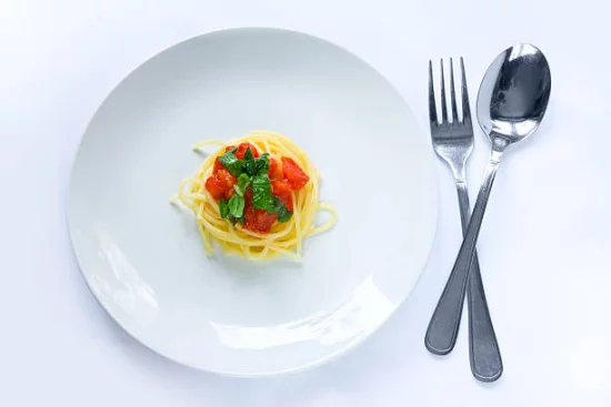 Appetit zuegeln Essen in kleinen Mengen langsam kauen voll genießen Spagetti mit Tomaten Basilikumblätter