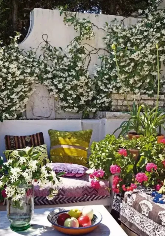 Feminine Outdoor-Bereiche Terrasse Sichtschutz Ziegelwand viele Blumen bequeme Sitzmöbel bunte Kissen romantische Atmosphaere