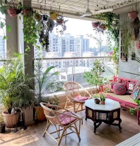 Feminine Outdoor-Bereiche verglaste Terrasse Sitzbank kleiner Tisch zwei Korbsessel sanfte Farben viele gruene Pflanzen