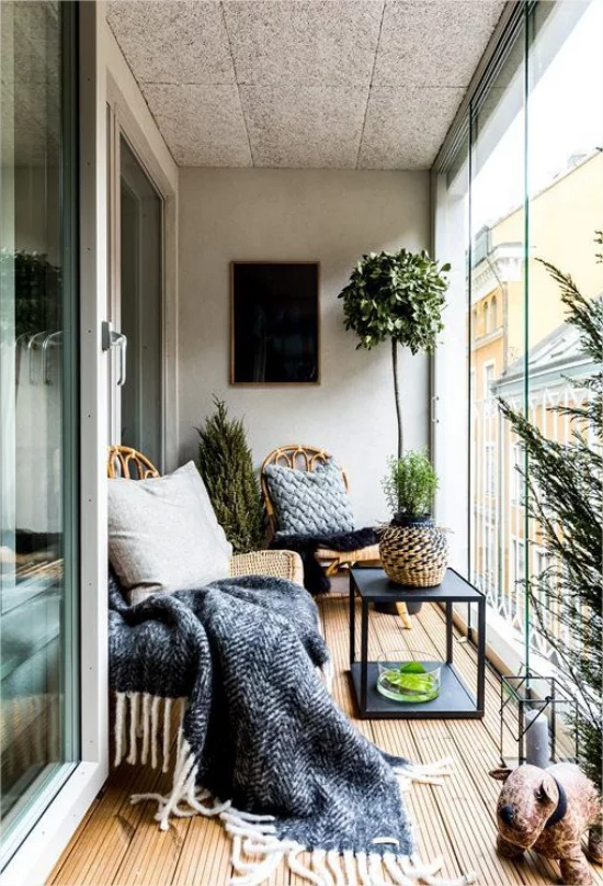 Gestaltungsideen fuer Balkon kleiner Raum verglast Tusch Sessel Wolldecke Kissen Gruenpflanzen
