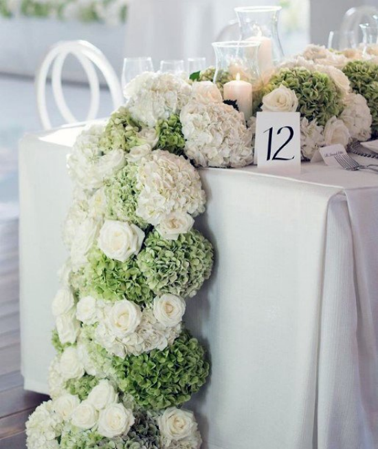 Hochzeitsdeko mit Hortensien Girlande aus weißen gruenen Blüten ueppiges Design auf den Tisch