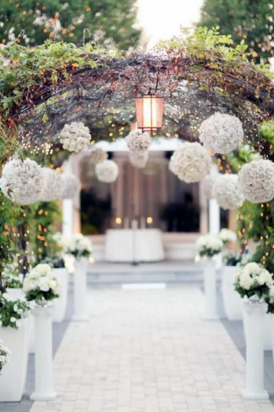 Hochzeitsdeko mit Hortensien durch einen praechtig geschmueckten Blumenbogen zusammen gehen