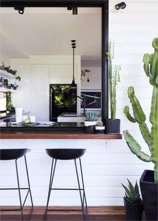 Indoor-Outdoor-Kuechen weites Fenster elegante Hocker aus Metall gruener Kaktus im Topf