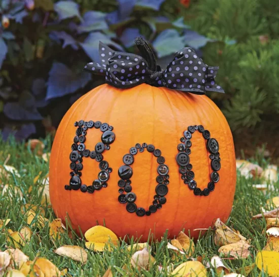 Herbstdeko mit Kuerbissen Boo mit schwarzen Knoepfen schwarze Schleife im Garten