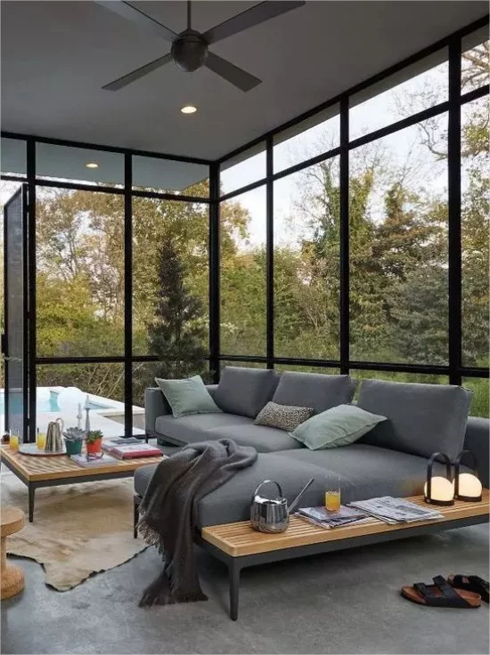 Moderne Glasveranda gemuetlicher Raum in Grau Sofa Kuscheldecke herrlicher Blick nach außen
