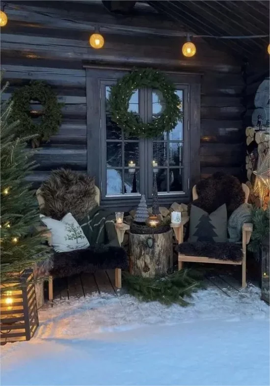 Winterdeko draussen dekorierte Veranda Lichter Tannenbaum Holzsessel Baumstumpf Kissen