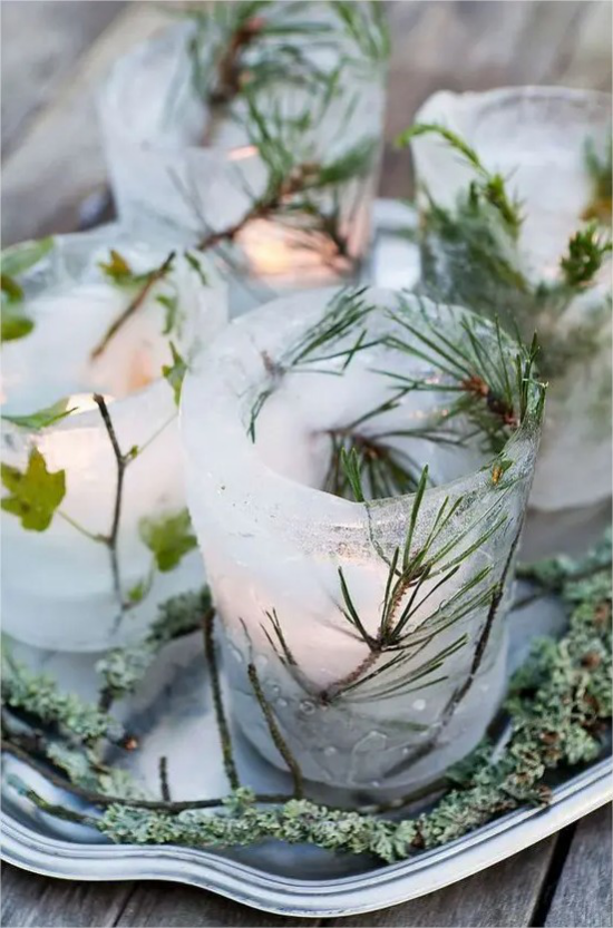 Gefrorene Weihnachtsdeko draussen gruene Tannenblaetter Efeu im Eis Teelichter