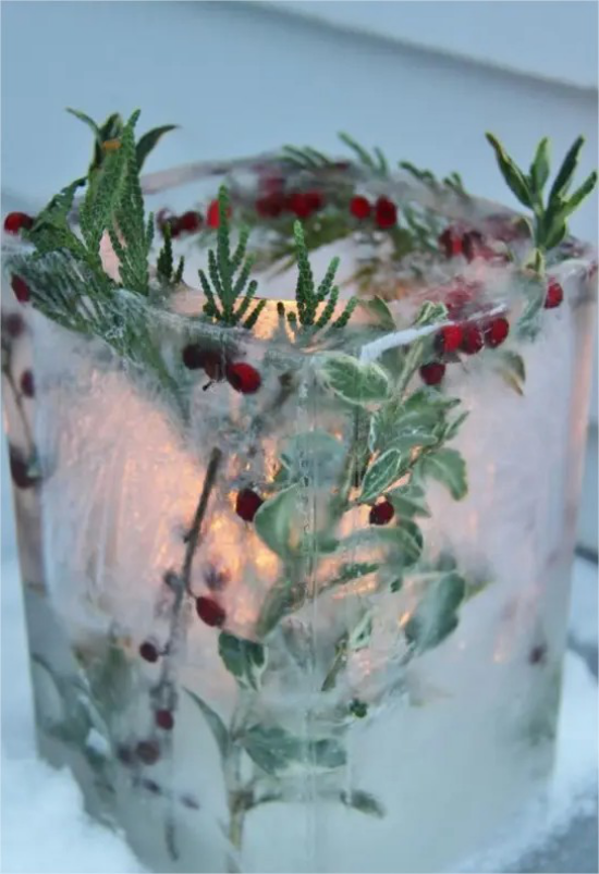 Gefrorene Weihnachtsdeko draussen rote Beeren gruene Blaetter in Glasform Windlicht