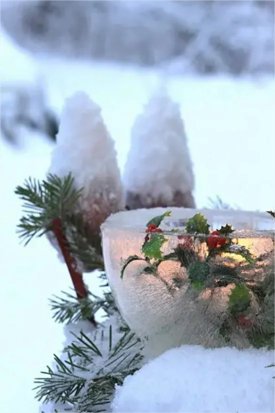 Gefrorene Weihnachtsdeko draussen schoenes Windlicht rote Beeren gruene Blaetter im Garten