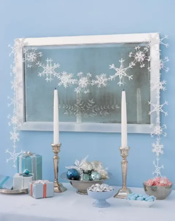Mit Schneeflocken dekorieren Weihnachtsdeko zwei weisse Kerzen Kugeln Girlande am Spiegel