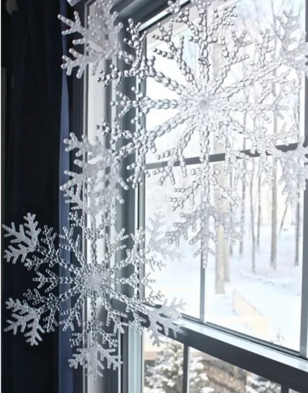 Mit Schneeflocken dekorieren kleine weisse Kristalle am Fenster