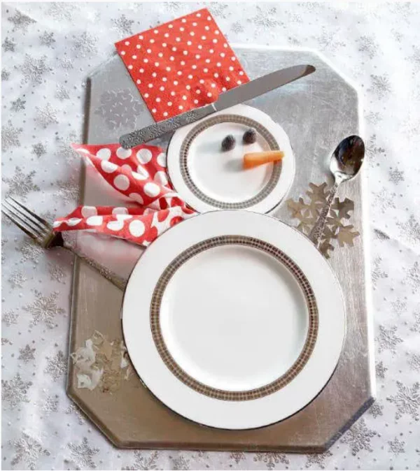 Schneemänner basteln lustige Weihnachtsdeko auf dem Esstisch zwei weisse Telle rote Serviette