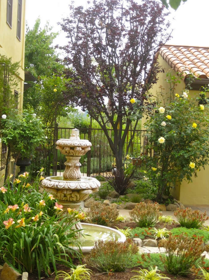 mediterraner Garten mit Gartenbrunnen und schönen Gartenbeeten