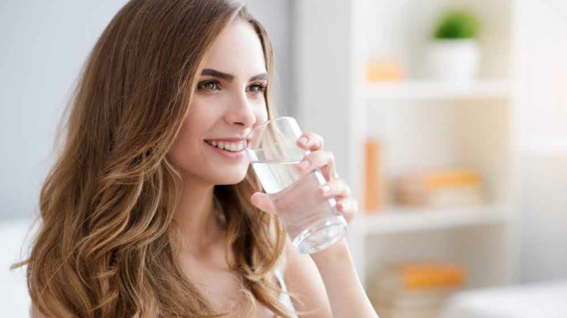 junge Frau trinkt Wasser aus einem Glas 