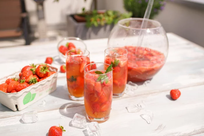 Fruchtbowle Rezept große Glasschüssel und Gläser voll mit Erdbeerbowle
