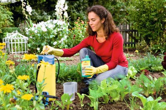 junge Frau verwendet chemisch Mittel im Garten 