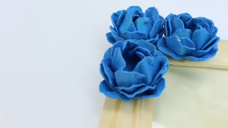 blaue Rosen aus Eierkarton auf einem Holzrahmen 