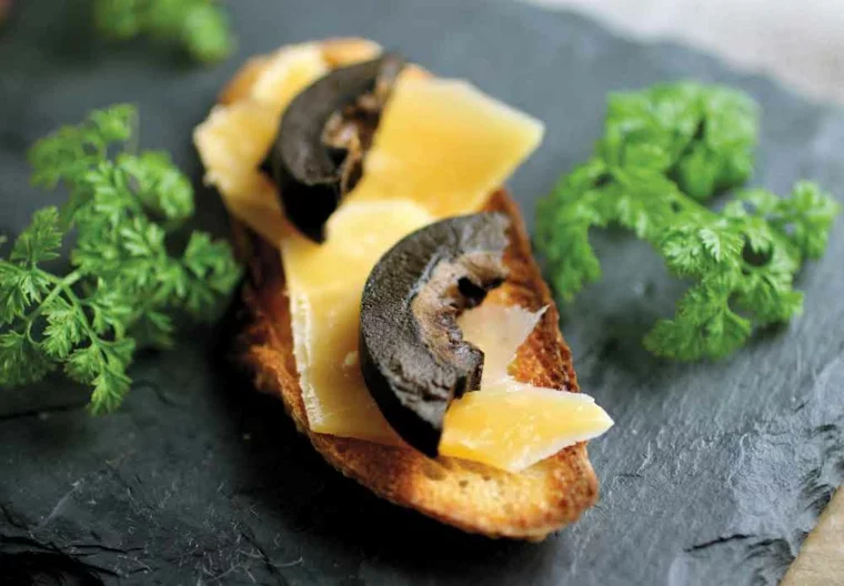 schwarze Walnüsse auf Toast mit Käse und Petersilie 