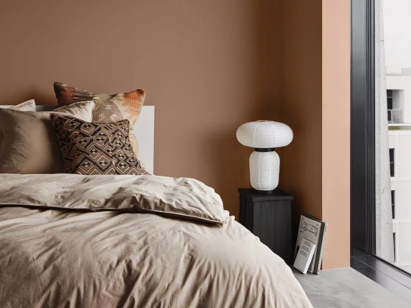 warme Töne im Schlafzimmer Cappuccino als Wandfarbe ist mit Beige und anderen Brauntönen der Bettwäsche kombiniert