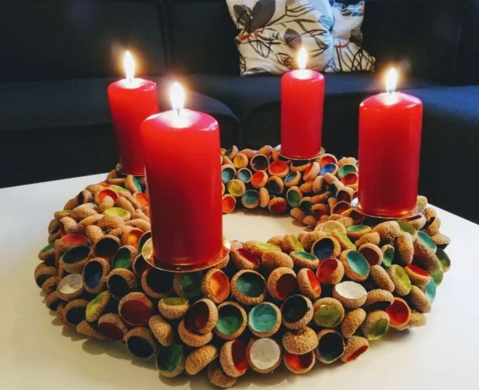 Adventskranz selber machen mit vier roten Kerzen und bunt gemalten Eicheln