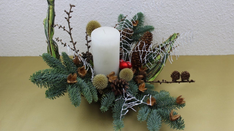 Eine weiße Kerze und viel Tannengrün Weihnachtsgestecke selber basteln