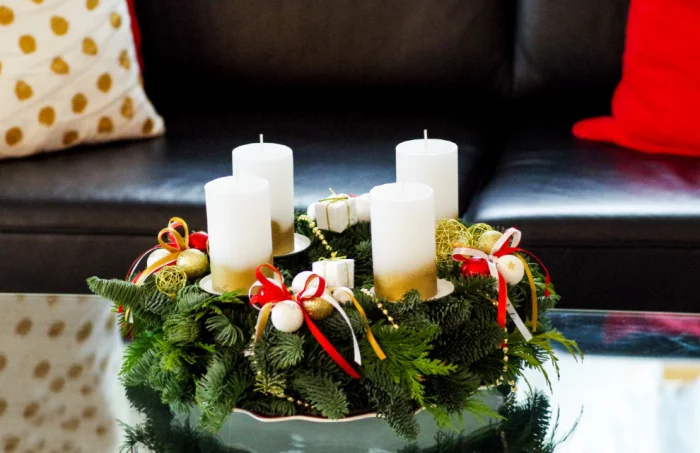 Traditioneller Adventskranz mit vier weißen Kerzen Tannengrün und rote Schleifen