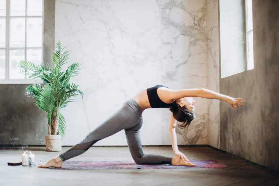  junge Frau macht Yoga Übungen zu Hause steht in Balance