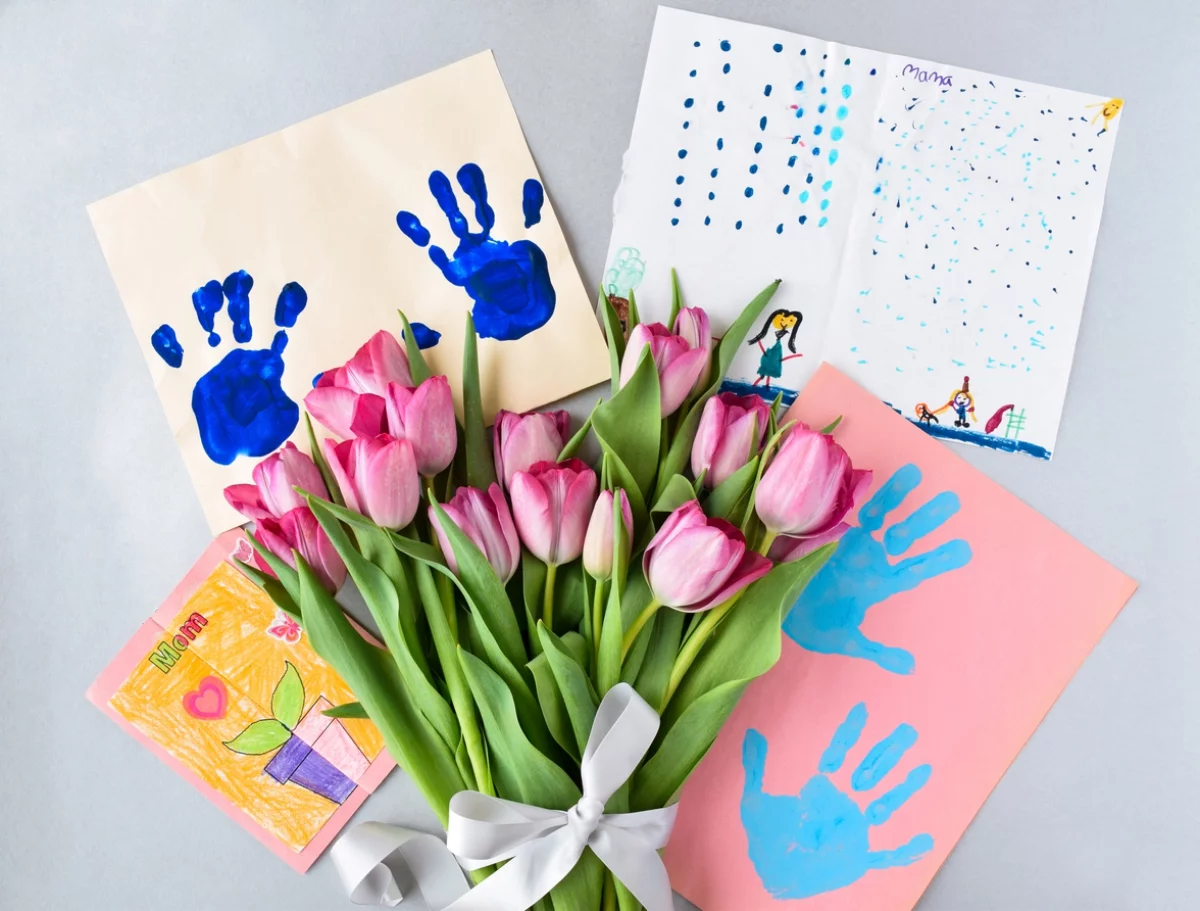 Kinderzeichnungen und ein Strauß rosa Tulpen 