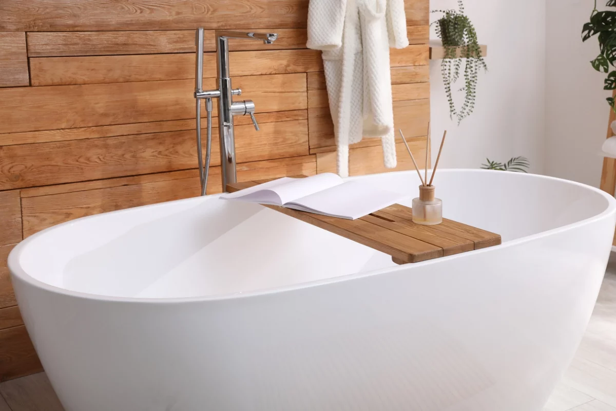 weiße freistehende Badewanne mit Ablage für Badkosmetika