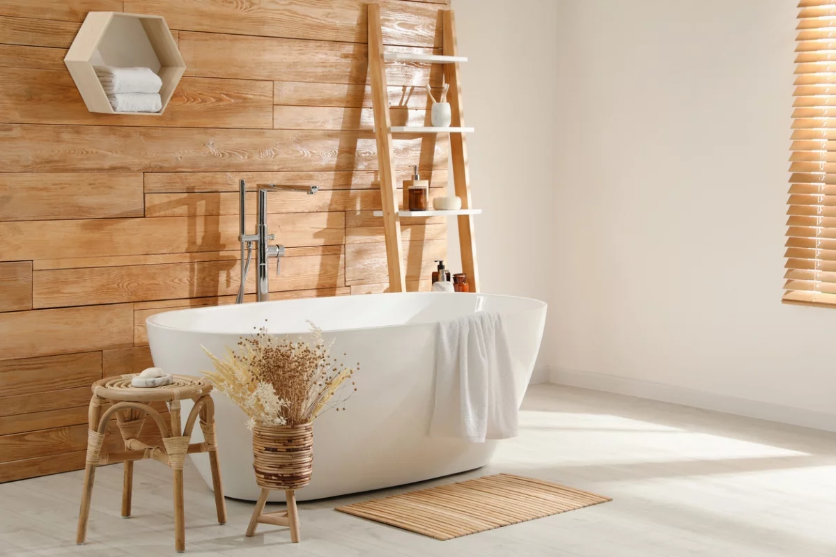 weiße freistehende Badewanne vor einer Holzwand