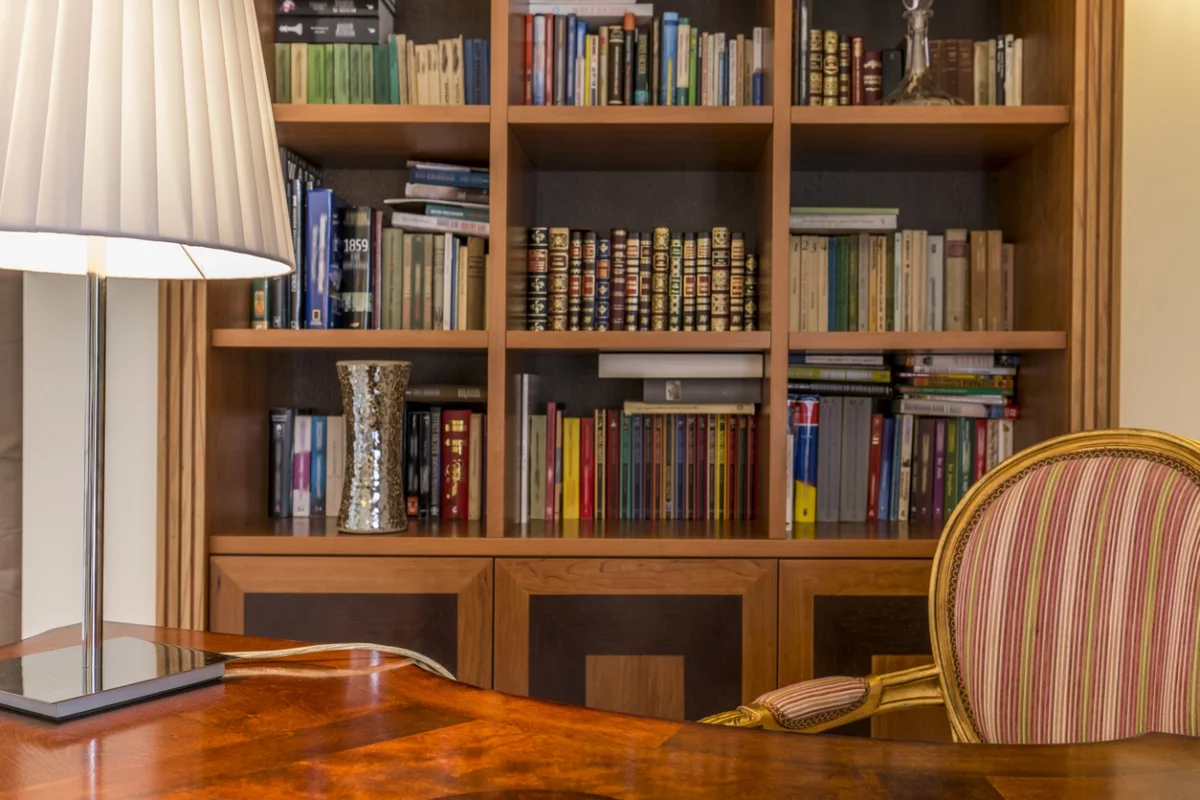 Gemütliches Homeoffice - Bücherregal im Hintergrund vorne Schreibtisch mit Lampe