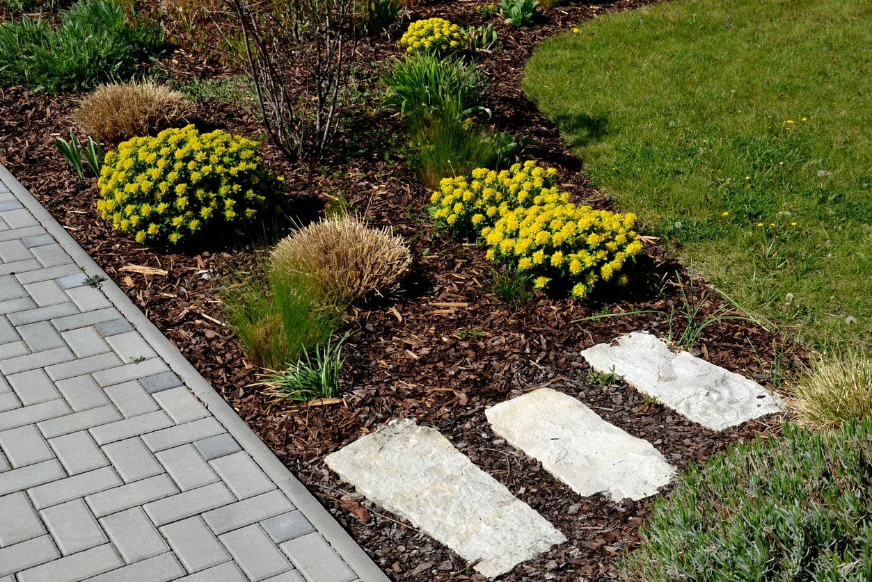 modernes Gartendesign mit Steinplatten und gelben Blumen