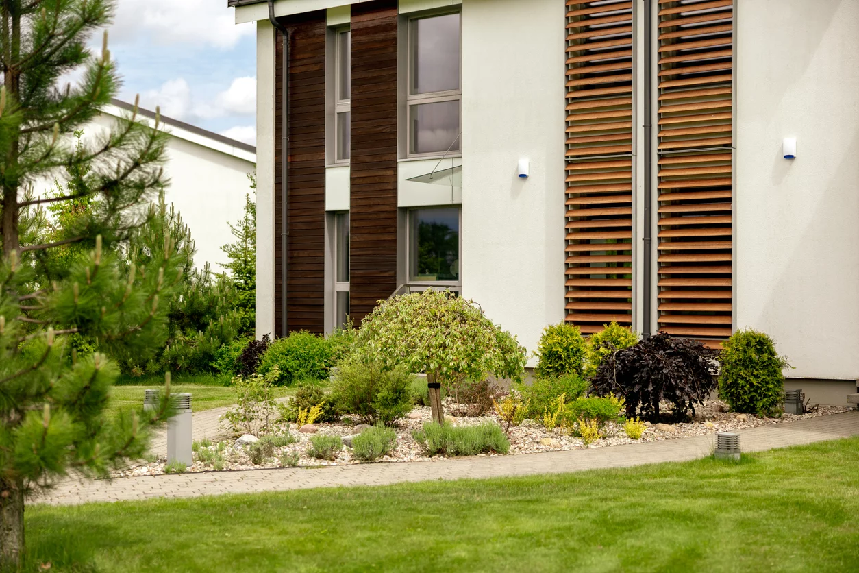 Moderner Garten mit grünen Pflanzen neben einem modernen Haus