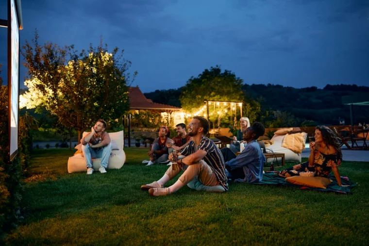 Junge Leute sitzen vor dem Fernseher auf dem Rasen