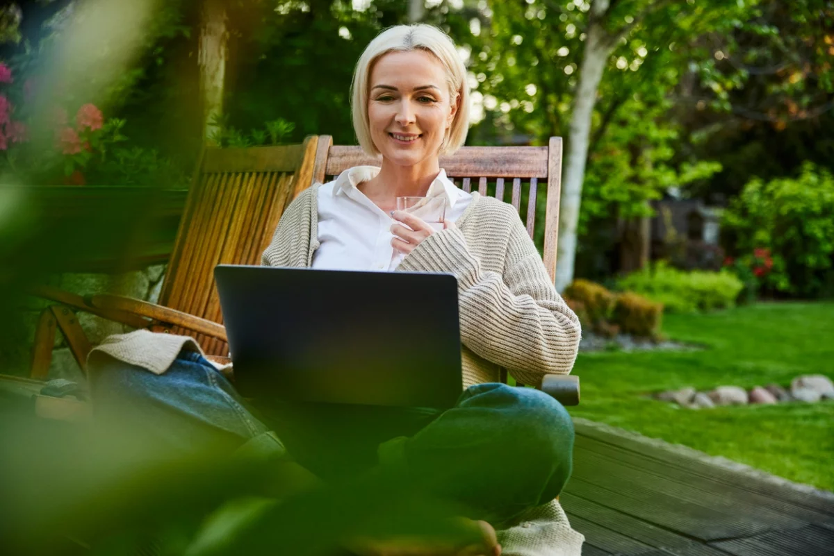  junge Frau mit dem Laptop in der Sitzecke im Garten