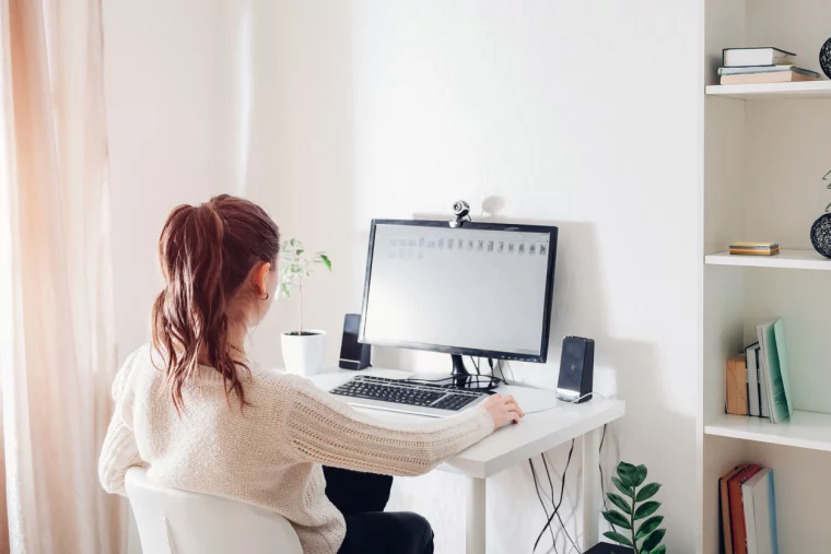 Junge Frau arbeitet am kleinen PC-Schreibtisch