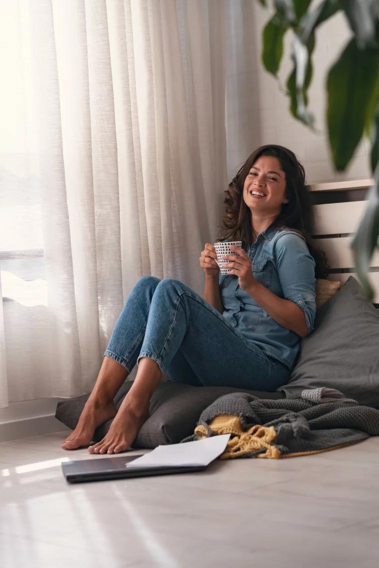 Junges Mädchen sitzt in der Ecke mit Kaffeetasse in der Hand